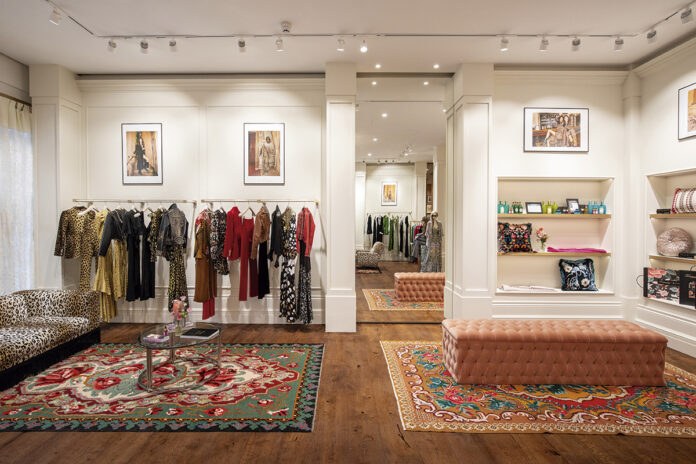 Inside the Aurelia and Rose boutique — clothing rails, framed fashion art and a pink velvet bench