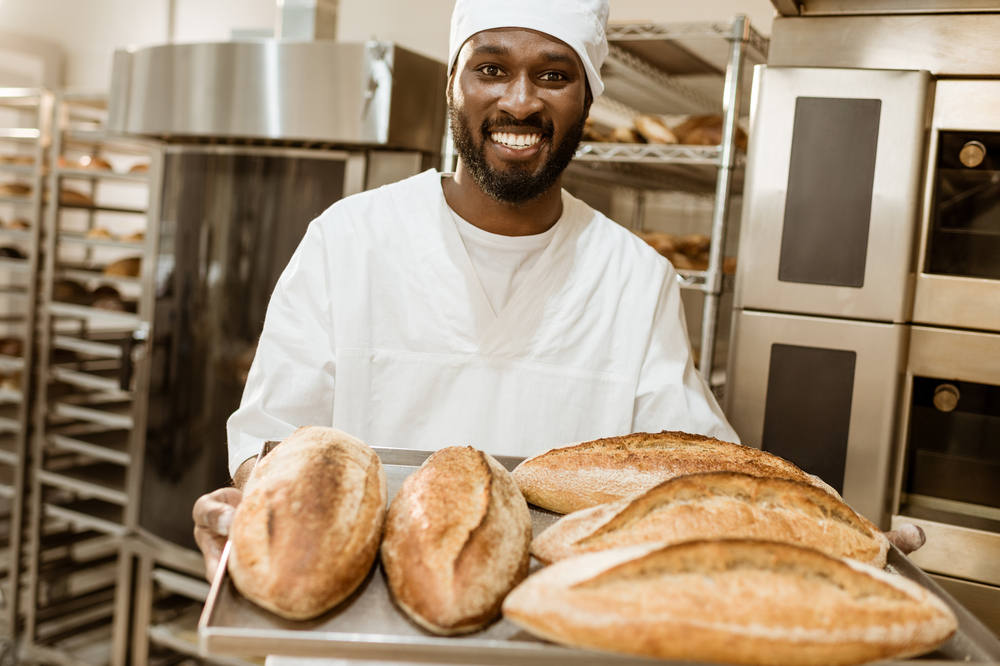 Our baker holding a tray of freshly baked sourdough loaves