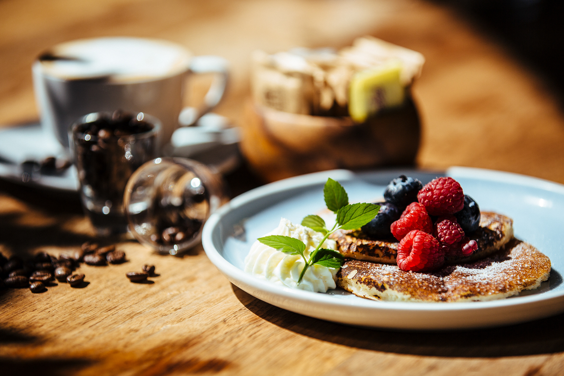 Pancakes topped with fresh berries and cream, served with coffee