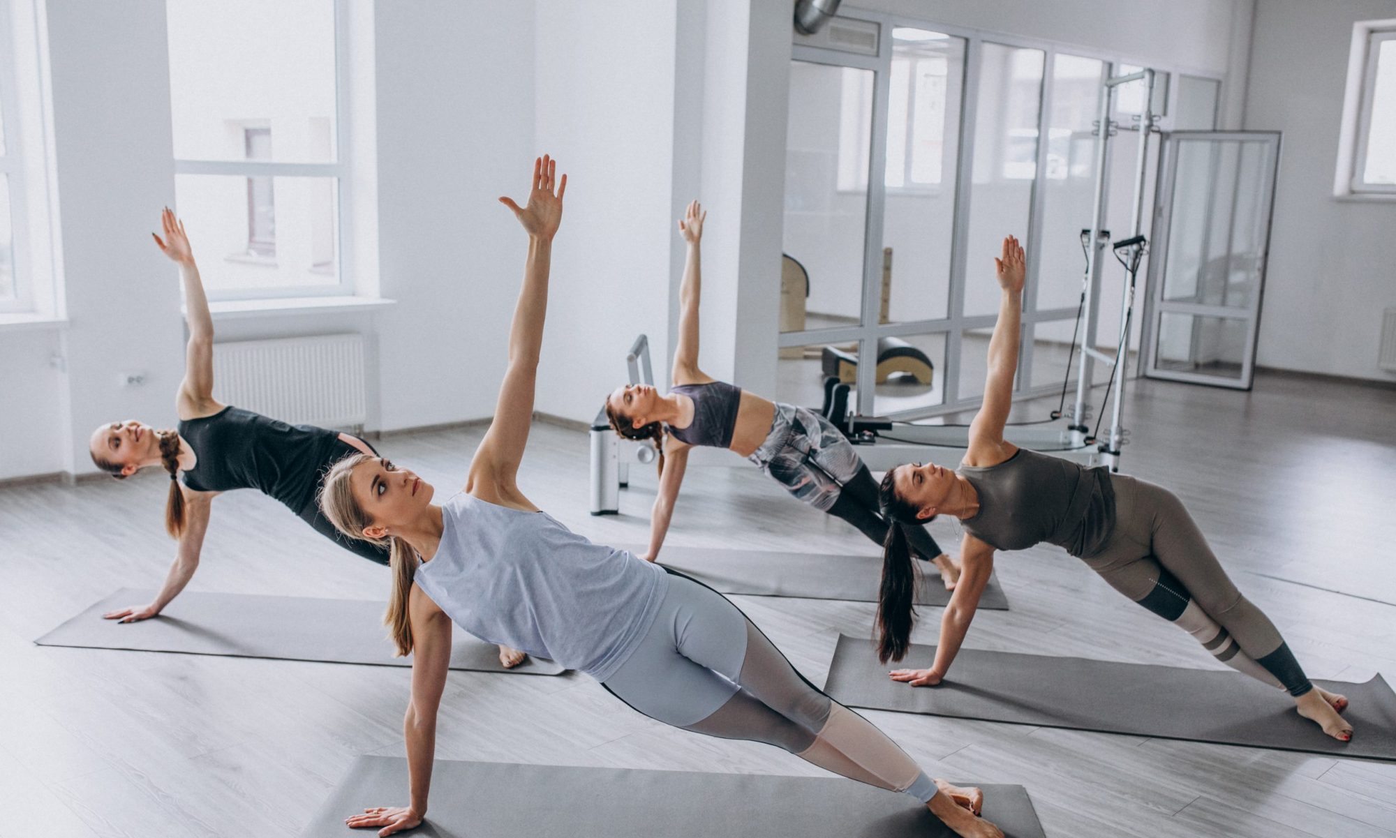Group yoga and mobility class holding side plank poses in a bright studio