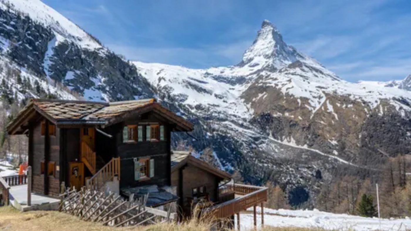 Wooden lodge chalets below a sharp snow-capped summit at dawn