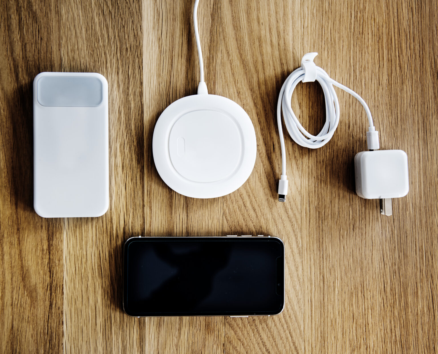 Phone accessories laid out on a table — power bank, wireless charger, cable and charger