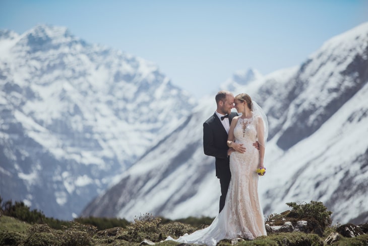 Bride and groom holding each other in front of snow-covered Himalayan peaks