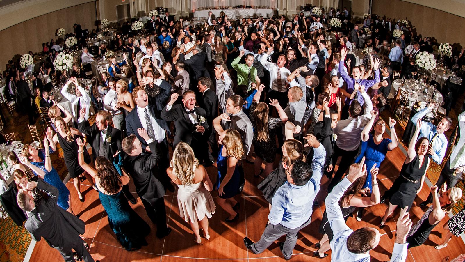 Wedding guests dancing together on a packed reception dance floor